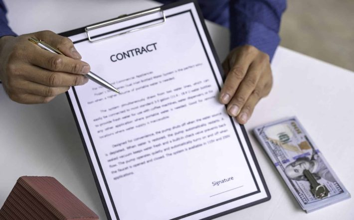 Businessman signing a document or application form in a folder, Businessmen hand's pointing where to sign a contract, legal papers or application form.